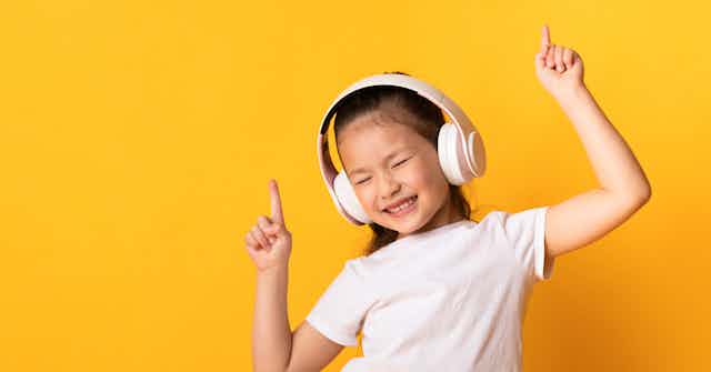 A girl in headphones is dancing with eyes closed.
