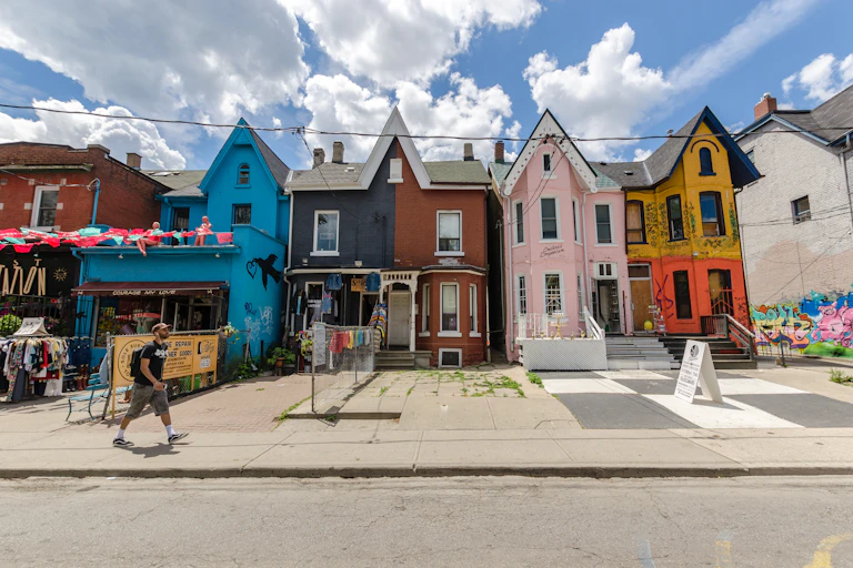 A man walks past a row of brightly coloured houses