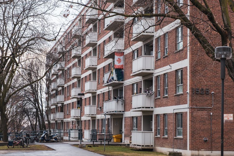 An older apartment building with a canadian flag flying from one balcony