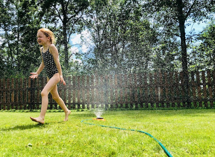 girl runs in sprinkler outside