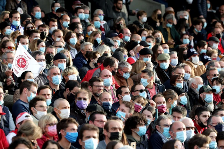 Foule de supporter assis et masqués mais très compacte.