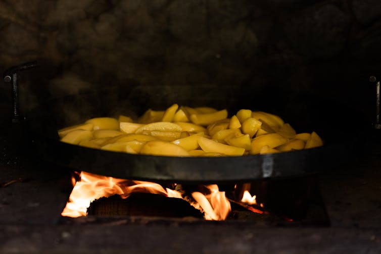 A pan of chips cooking on9 top of an open fire.