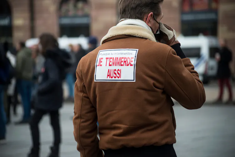 A man with a sign in French on his back