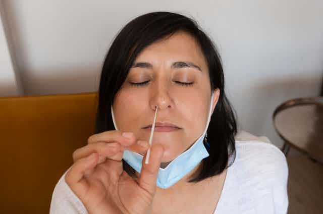 A woman swabbing her nose for a COVID test