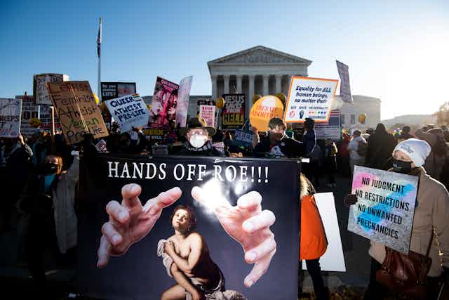 Protest posters are shown in front of the US Supreme Court building -- one says "Hands Off Roe!!"