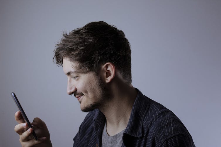 A man in profile looking at his mobile phone