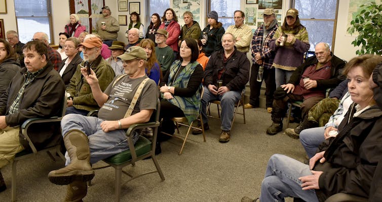 A group of people sit and stand in a meeting room