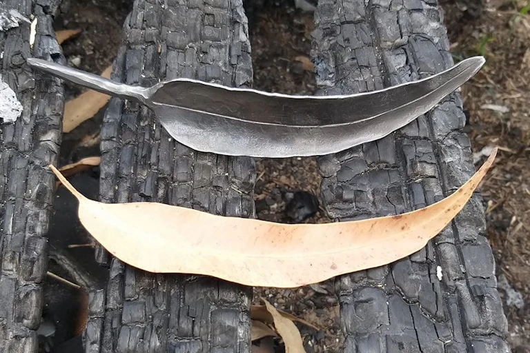 A metal gumleaf and a dried gumleaf.