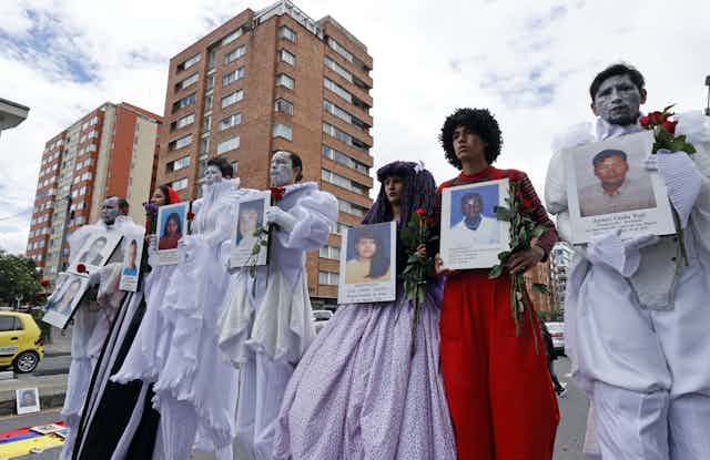 A group of Colombian men and women holding pictures of their relatives who are missing, believed murdered. Bogota, August 2021.