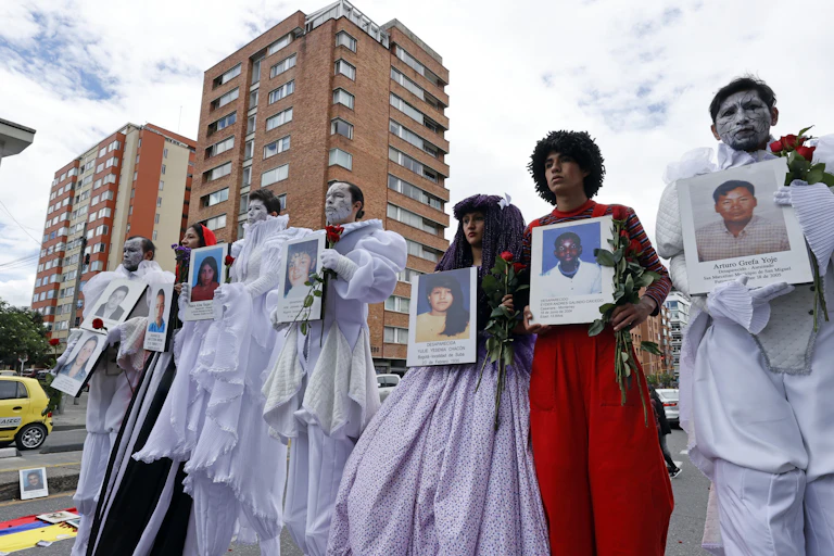 A group of Colombian men and women holding pictures of their relatives who are missing, believed murdered. Bogota, August 2021.