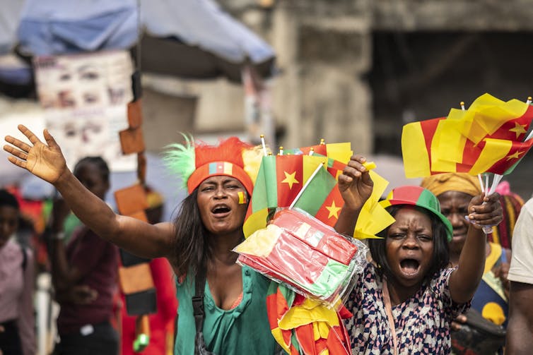 A stadium full of brightly coloured - in red, yellow and green clothes and make-up - fans cheer for Cameroon, blowing vuvuzelas and holding flags.