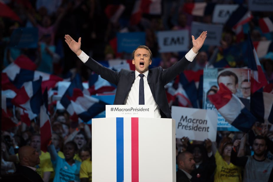 Emmanuel Macron holds his hands in the air at a political rally in 2017.