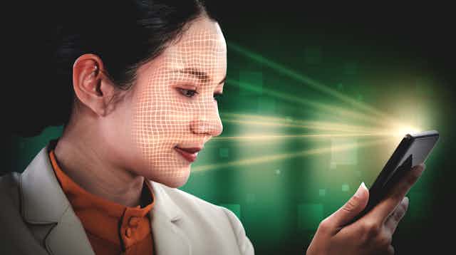 une femme tenant un téléphone portable qui scanne son visage.