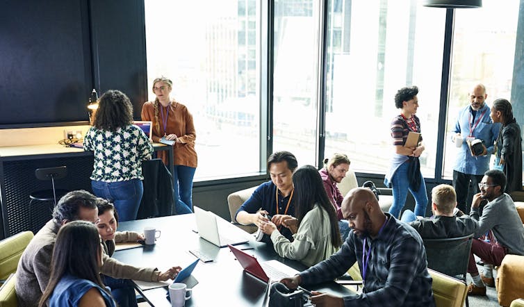 A diverse group of professionals, most of whom are young, meet in a modern conference room.