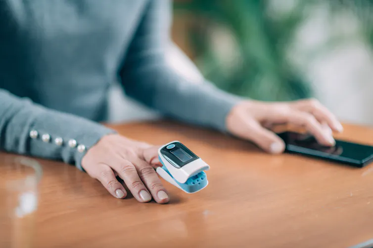 Woman at home with pulse oximeter on fingertip