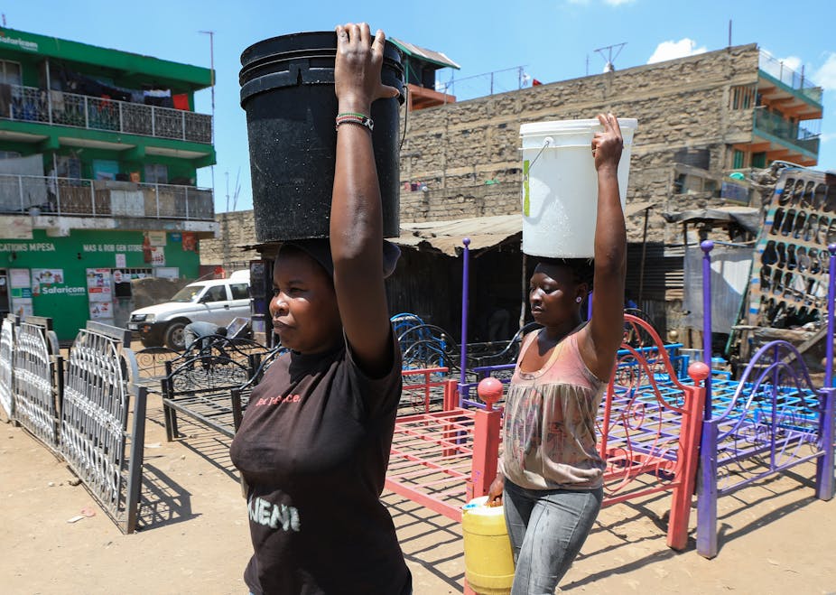 Women carry water buckets filled with water on their heads 
