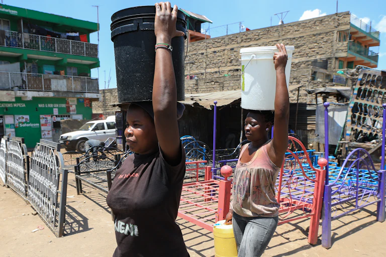 Women carry water buckets filled with water on their heads