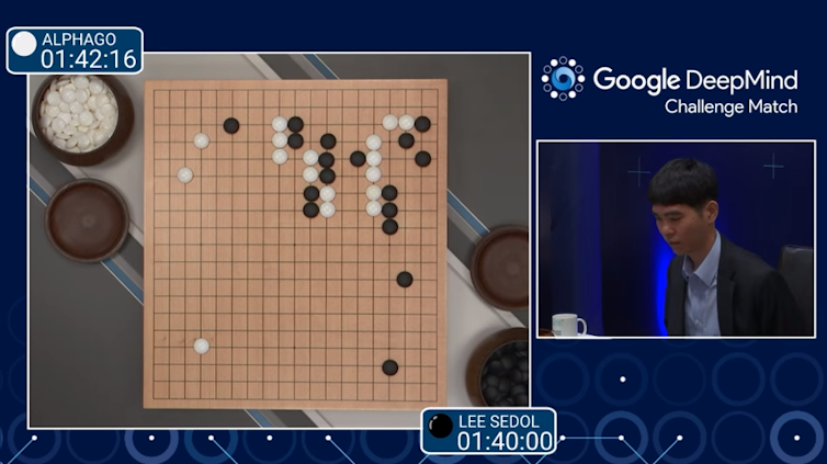 Partie de Go entre AlphaGo et le joueur Lee Sedol ; un cadre de l’image montre le plateau de go vu de dessus, un autre cadre filme le joueur Lee Sedol