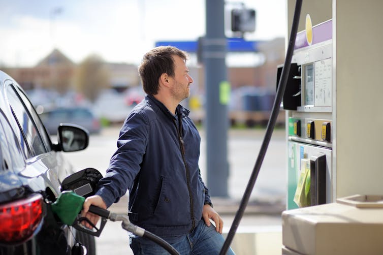 A person filling their car up at a petrol station.