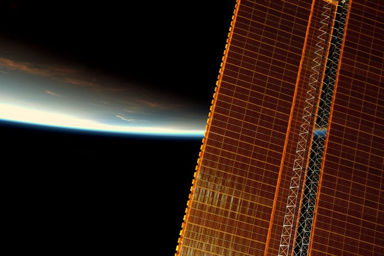 Une des baies de panneaux solaires de l’ISS, avec la terre à l’arrière-plan
