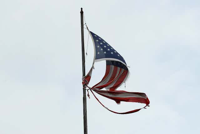 A torn U.S. flag flying from a pole
