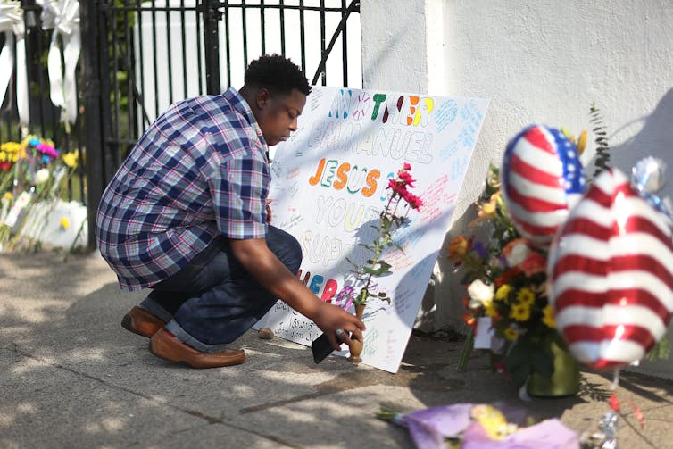 A man places a flower in front of a church where 9 people were killed in a shooting.