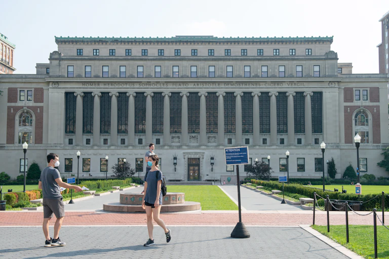 A pair of students walk across a university campus.