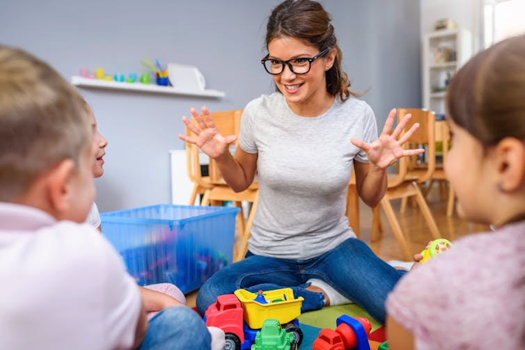 Childcare worker talking to kids.