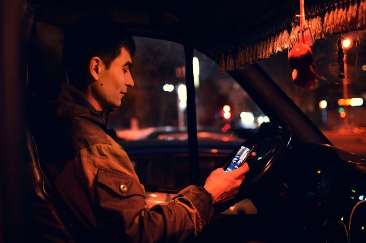 A man in a car looks at his phone.