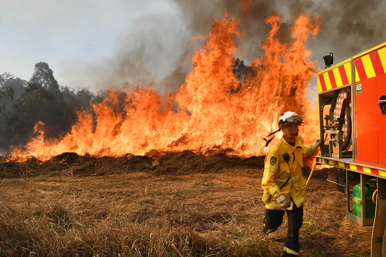 firefighter runs to truck with fire behind him
