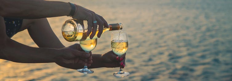 People pour wine into a glass.