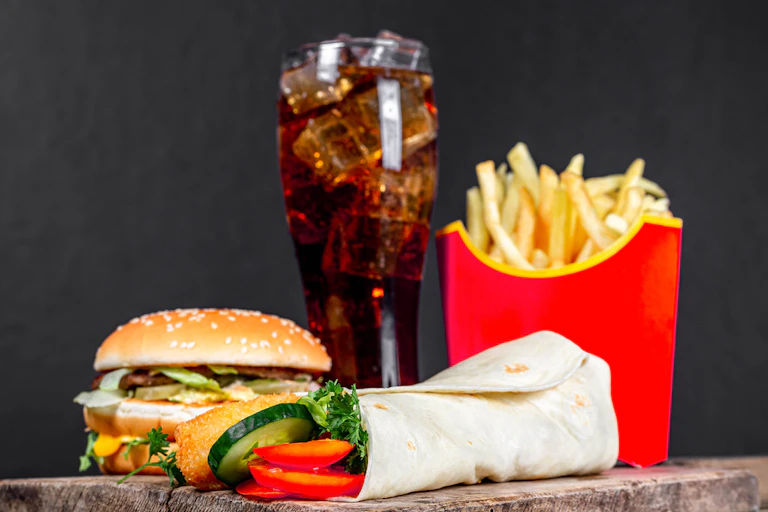 An image of a burger,potato chips and a glass of fizzy drink