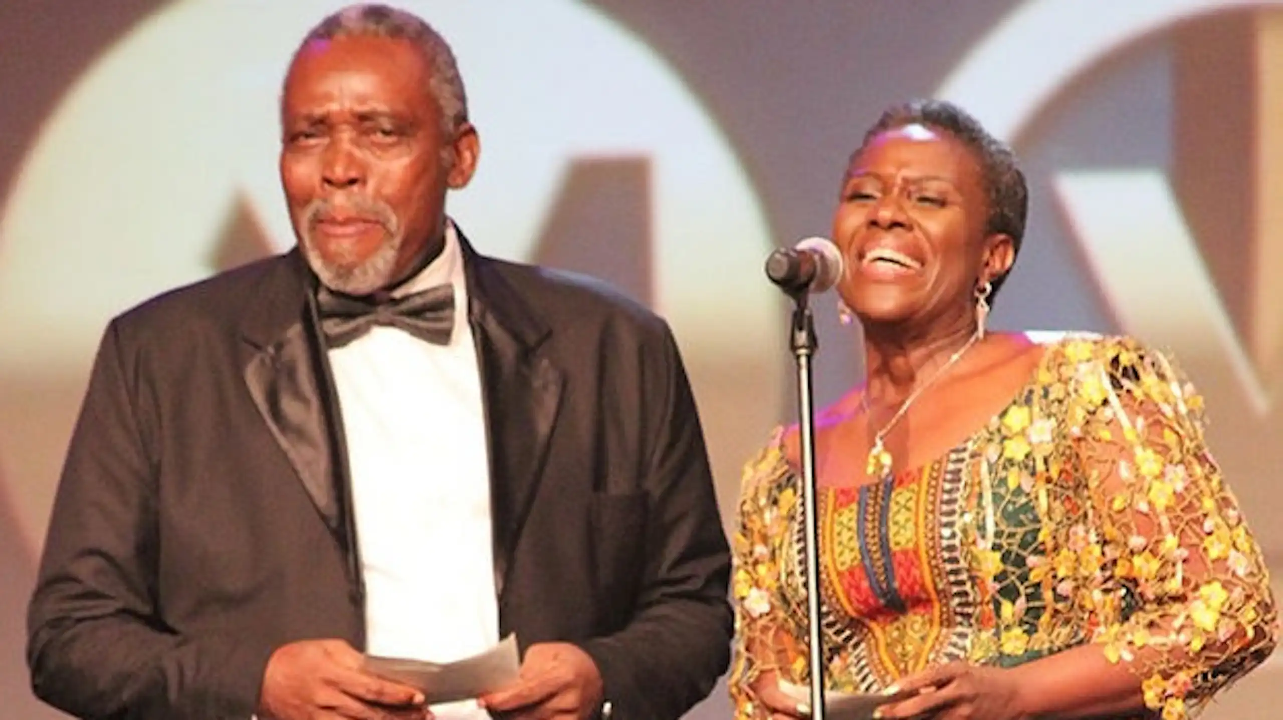 Man and woman on stage with a microphone receiving an award.