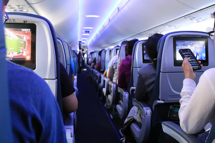 Passengers on an aircraft look at video screens