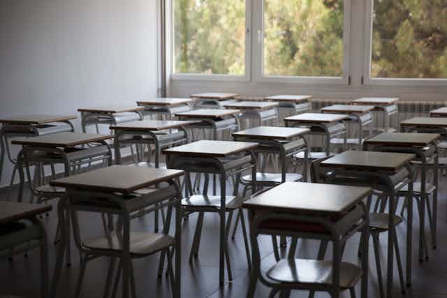 Rows of empty chairs and desks in a classroom.