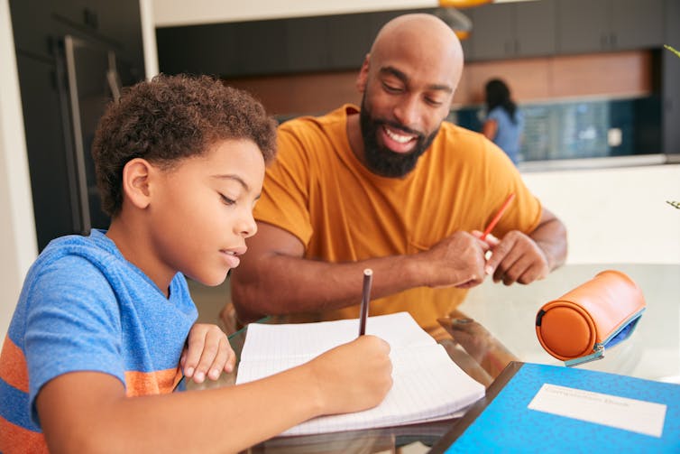 A father helps his son with his homework.