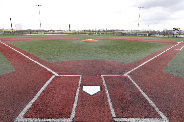 Image shows empty baseball field from a view behind home plate