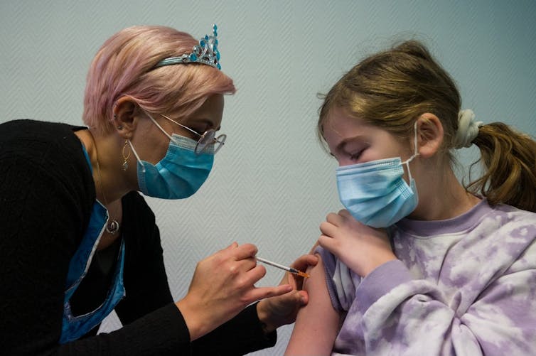 Une jeune fille se fait vacciner par une infirmière.