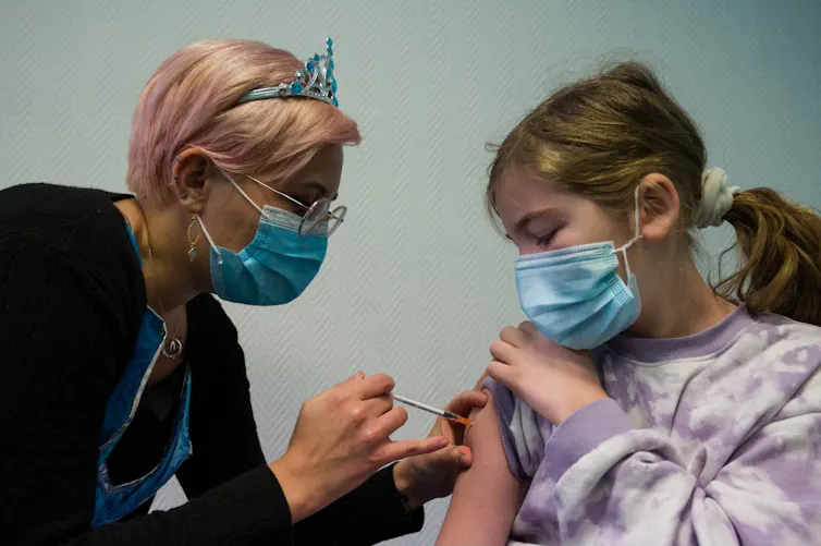 Une jeune fille se fait vacciner par une infirmière.
