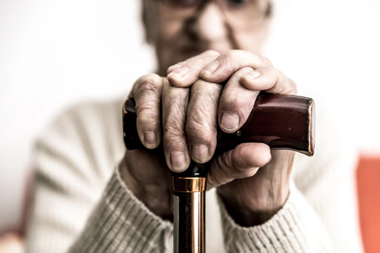 Older person holding their cane.