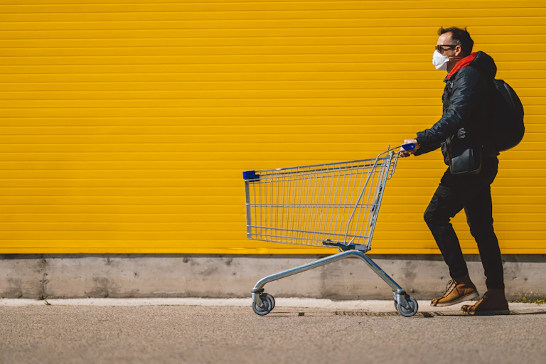 Man wearing face mask and pushing shopping trolley.