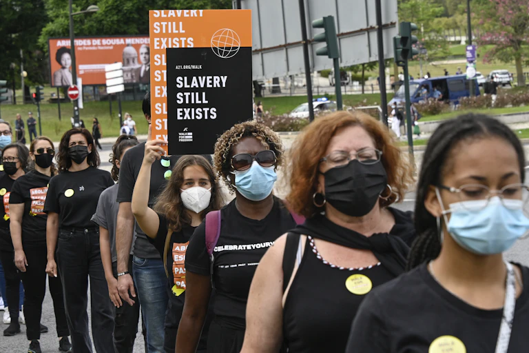 A group of people walk in a line holding signs against human trafficking