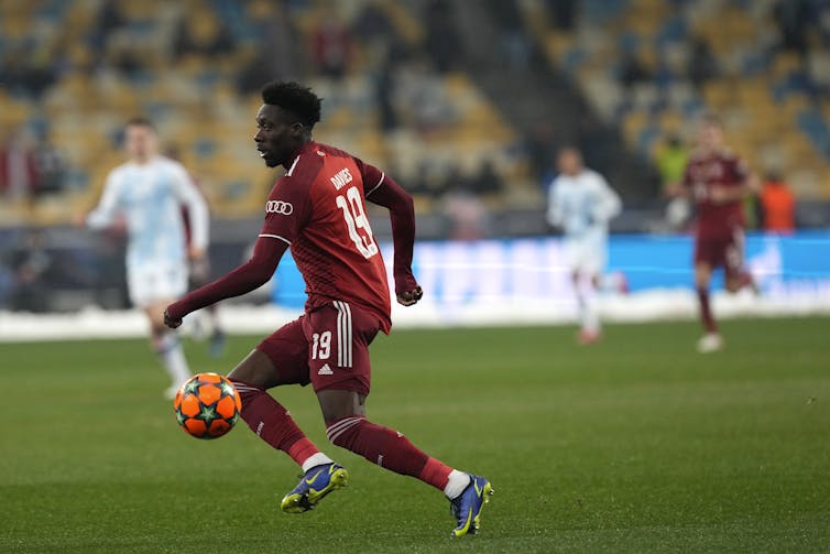 A soccer player on the field in a red uniform