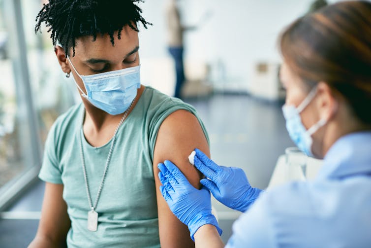 A young person wearing a face mask getting a vaccination