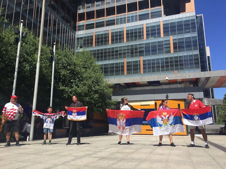 Supporters of Novak Djokovic hold Serbian flags.