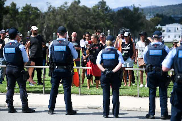 Police officers stand guard as protesters approach Parliament House during a rally in Canberra.