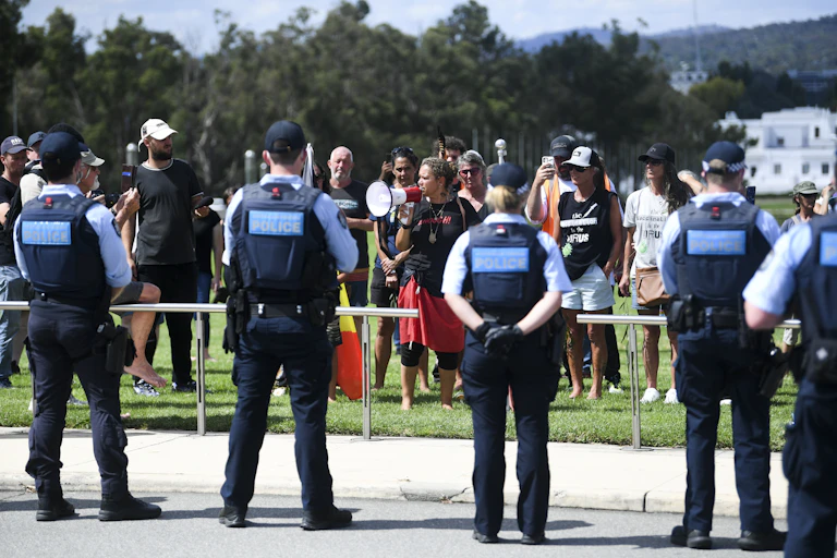 Police officers stand guard as protesters approach Parliament House during a rally in Canberra.