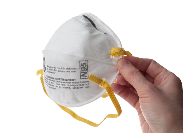 N95 respirator held up by hand
