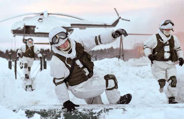 Russian soldiers wearing arctic uniforms take part in exercises after leaving a helicopter