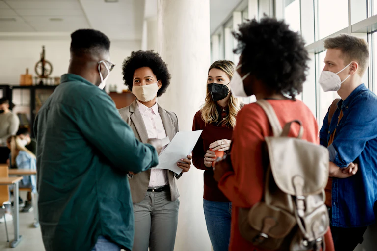 A group of people in face masks talking.